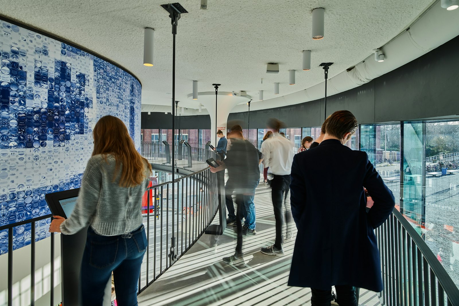 Visitors on the walkway past the Delft blue tiled wall inside THIS IS HOLLAND